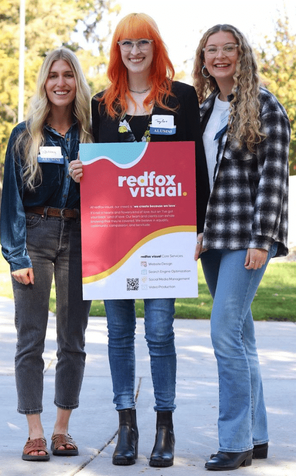 Photo of three redfox employees holding a redfox visual branded posterboard